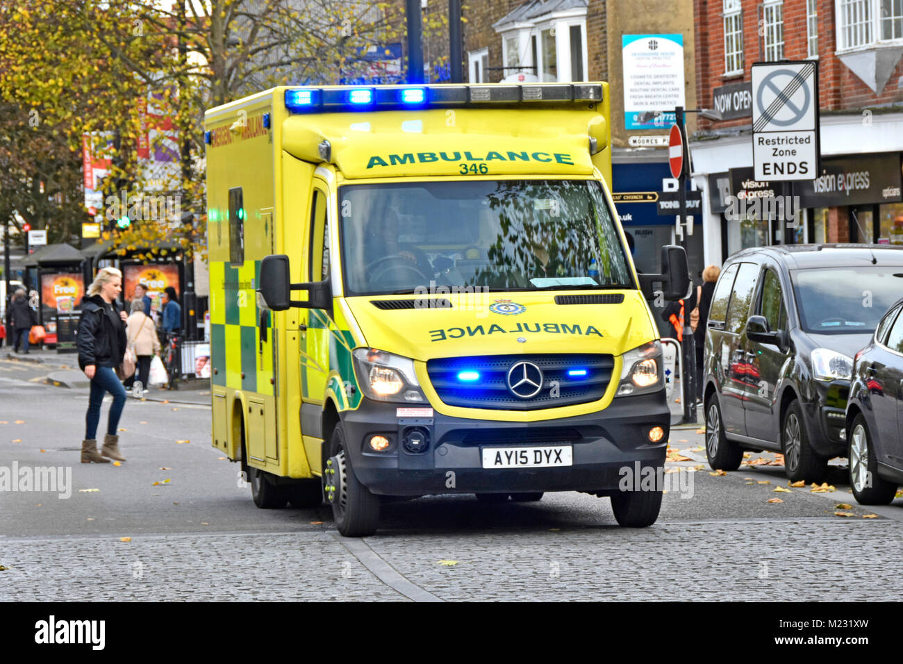 East of England blue light Emergency Ambulance Service NHS vehicle & crew on 999 journey pedestrians crossing High Street Brentwood Essex England UK Stock Photo