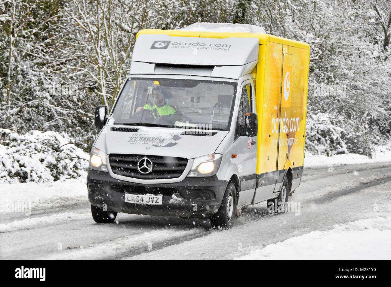Ocado internet food grocery supermarket delivery van on snow covered winter road making home delivery trips to online shopping customers England UK Stock Photo