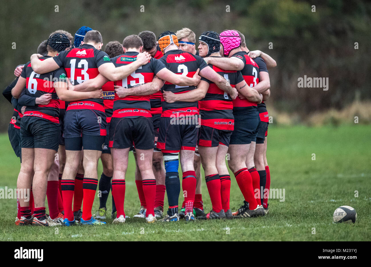 Male rugby union football players hug together with arms linked. Stock Photo