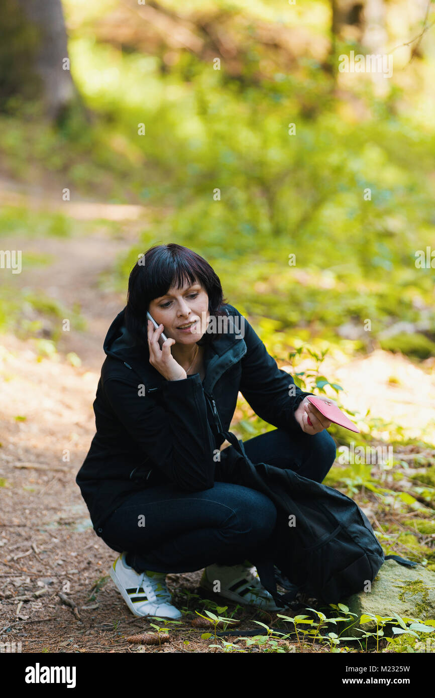 middle-age-woman-on-hiking-trip-lost-in-forest-calling-from-mobile-M2325W.jpg