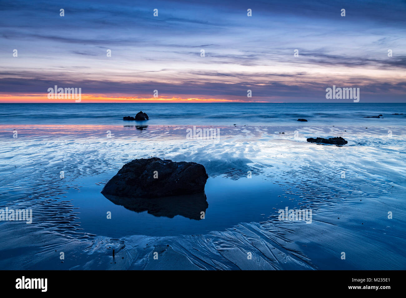 Rock in a tidal pool on the beach at dusk, Church Bay, Anglesey, North Wales Stock Photo