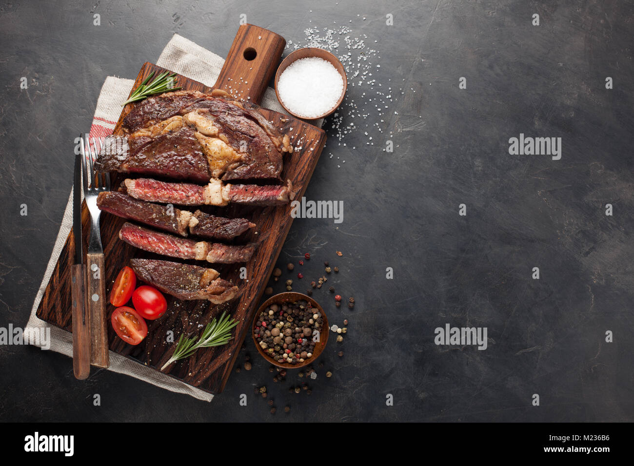 Grilled ribeye beef steak with red wine, herbs and spices on a dark ...