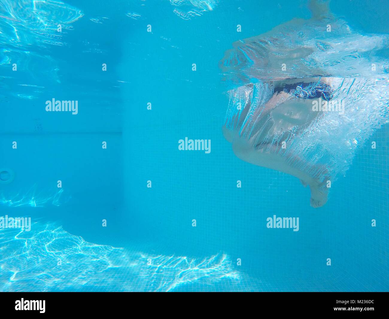 Underwater shot of unrecognizable person's legs in swimming pool.Clear blue water Stock Photo