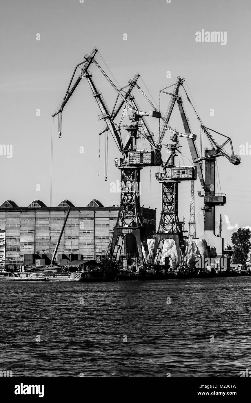 Gdansk shipyard, Poland. Retro style black and white. Cranes, old shipyard buildings, rusty structures. Stock Photo