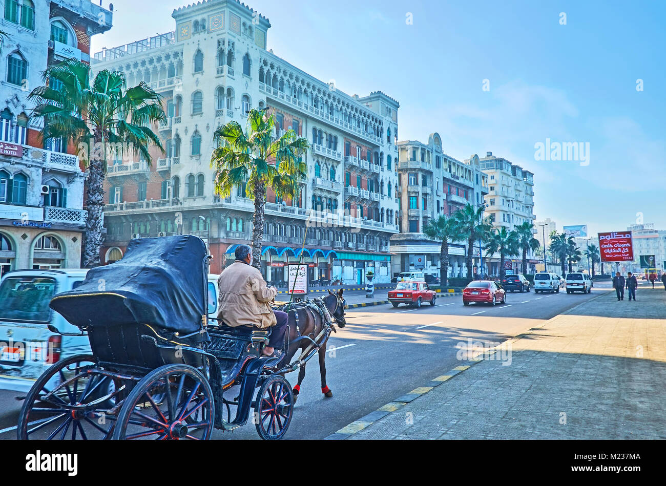 ALEXANDRIA, EGYPT - DECEMBER 18, 2017: The horse carriage rides along the Corniche avenue with a view on historic Little Venice mansion on background, Stock Photo