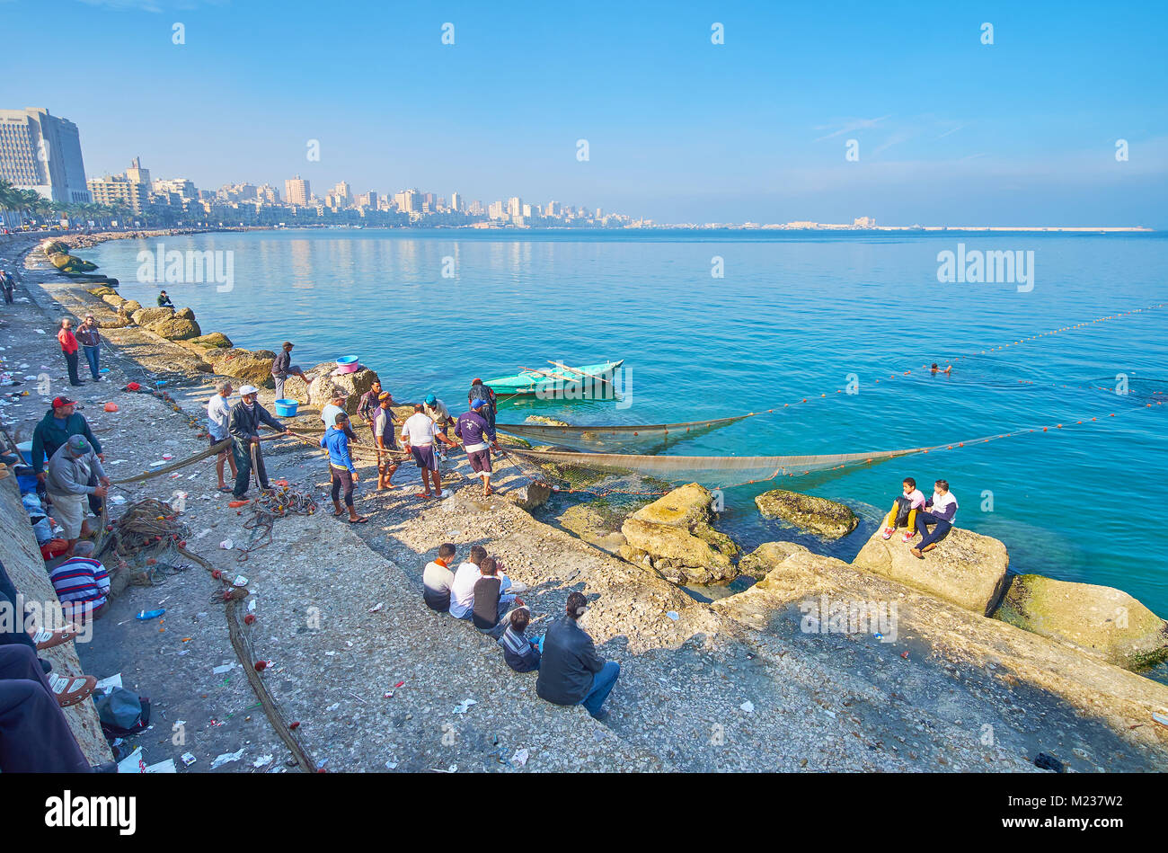 ALEXANDRIA, EGYPT - DECEMBER 17, 2017: The fishermen crew at work in the city center with a view on buildings on Corniche avenue, stretching along the Stock Photo