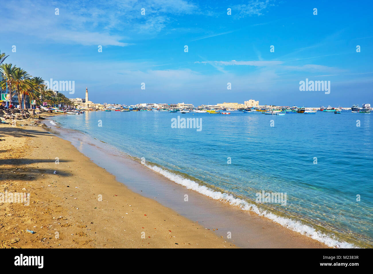 ALEXANDRIA, EGYPT - DECEMBER 17, 2017: The walk along the sea with aview on numerous fishing boats in Eastern harbor, Manar El Islam Mosque and Qaitba Stock Photo