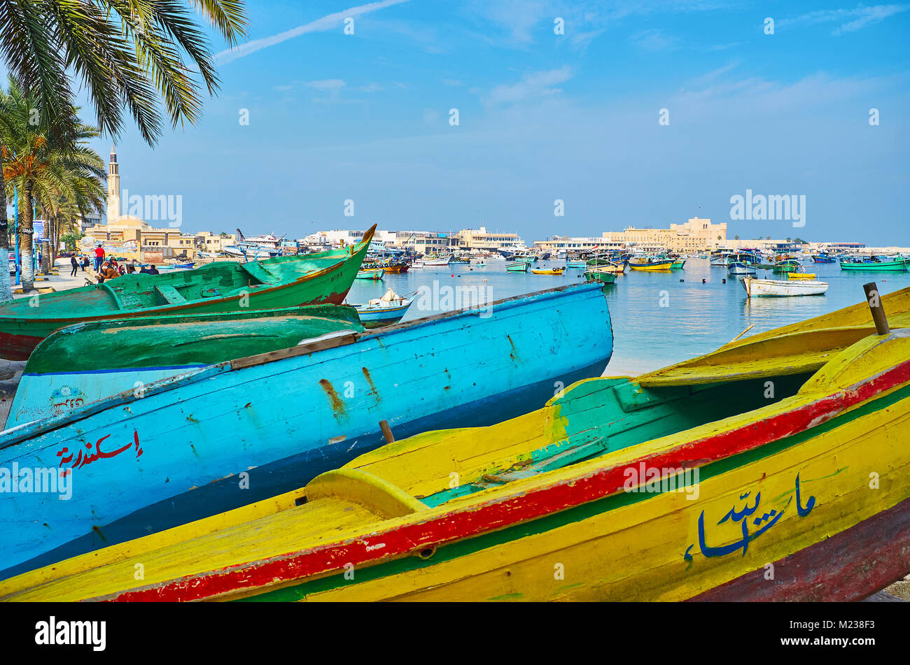 ALEXANDRIA, EGYPT - DECEMBER 17, 2017: The colored fishing  boats stands along the Corniche promenade, the Eastern harbor and Qaitbay citadel are seen Stock Photo