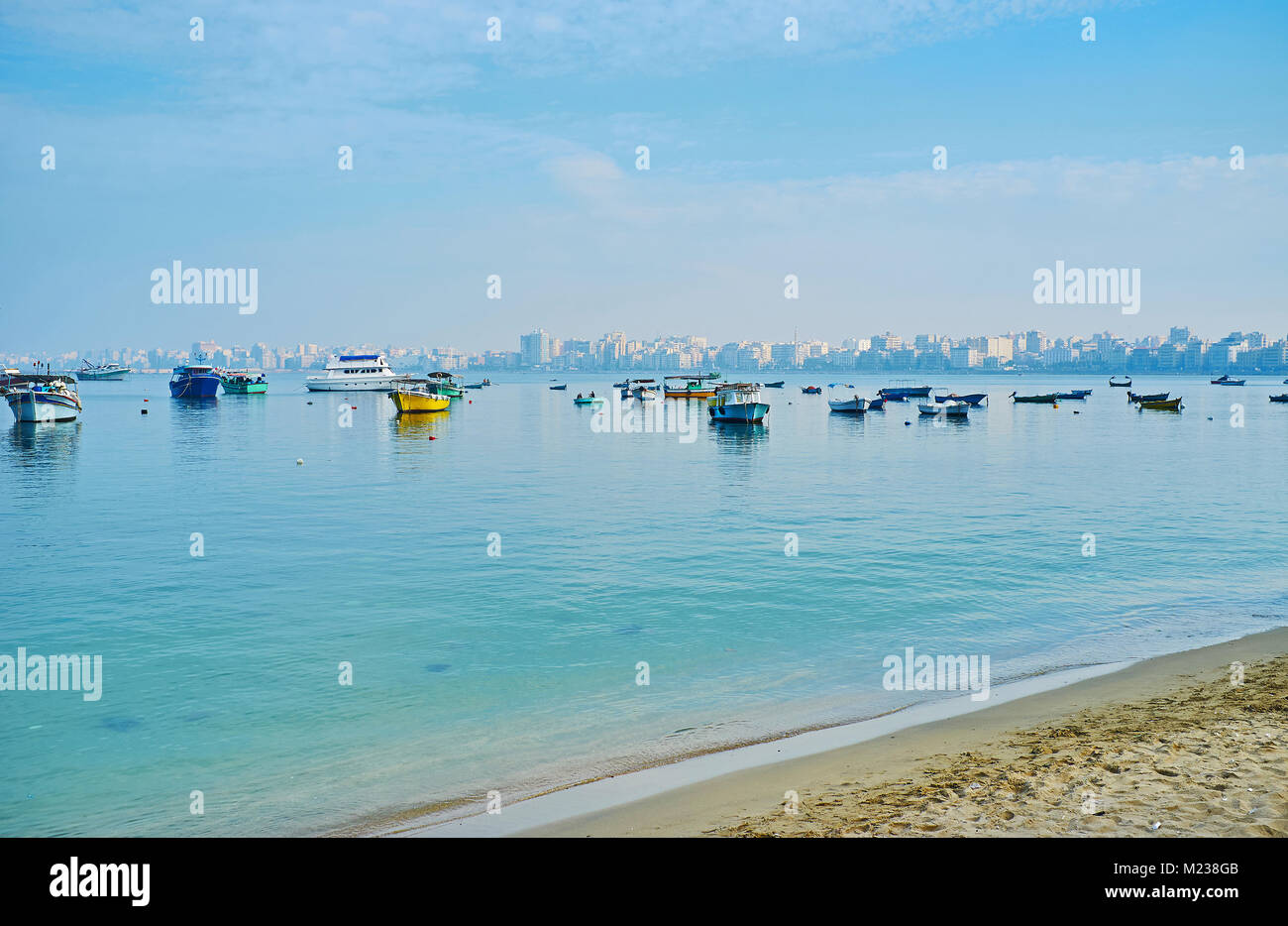 The walk along the sand shore of Eastern harbor with a view on foogy buildings on background, Alexandria, Egypt. Stock Photo