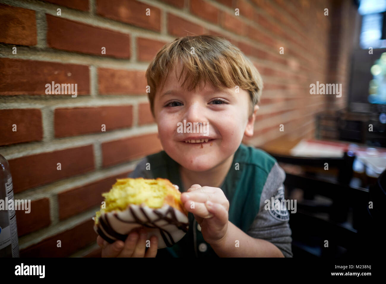 New York City Manhattan, 8th Avenue boy eating large donut cake Stock Photo