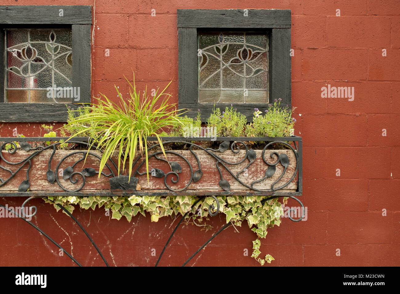 Red brick wall with stained glass windows and antique wrought iron planter Stock Photo