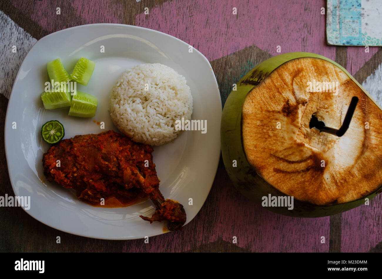 Typical Indonesian Dish: Nasi Ayam Plecing (Chicken with rice and special sauce) and young coconut bird's eye. Stock Photo