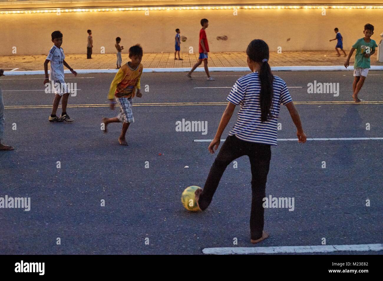 Cambodian girl and Children on floating house, Kompong Chhnang, Cambodia playing football in front of Royal Palace, Phnom Penh, Cambodia Stock Photo