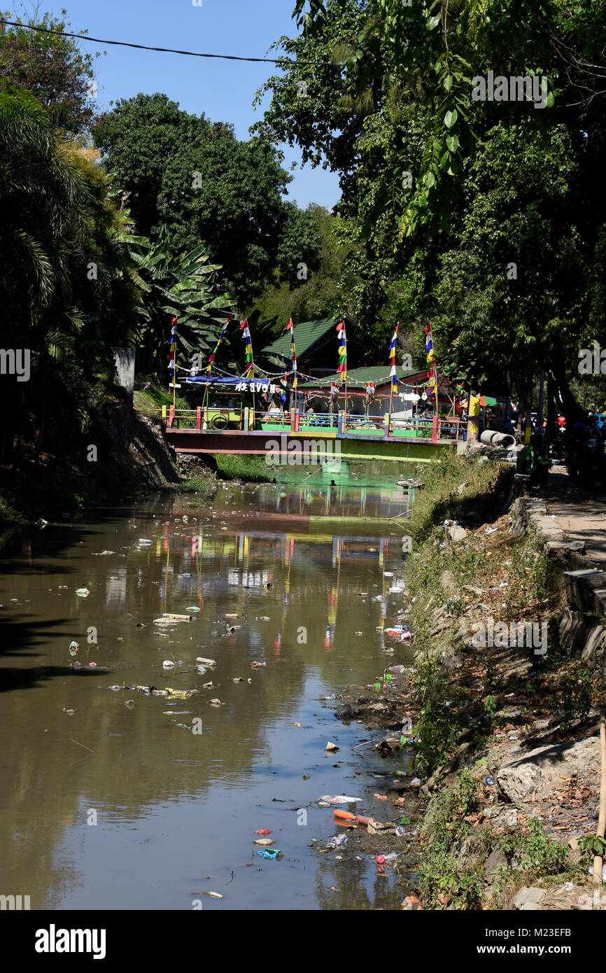 Rubbish flowing down a small river in Indonesia, next to a slum area called the painted village Stock Photo