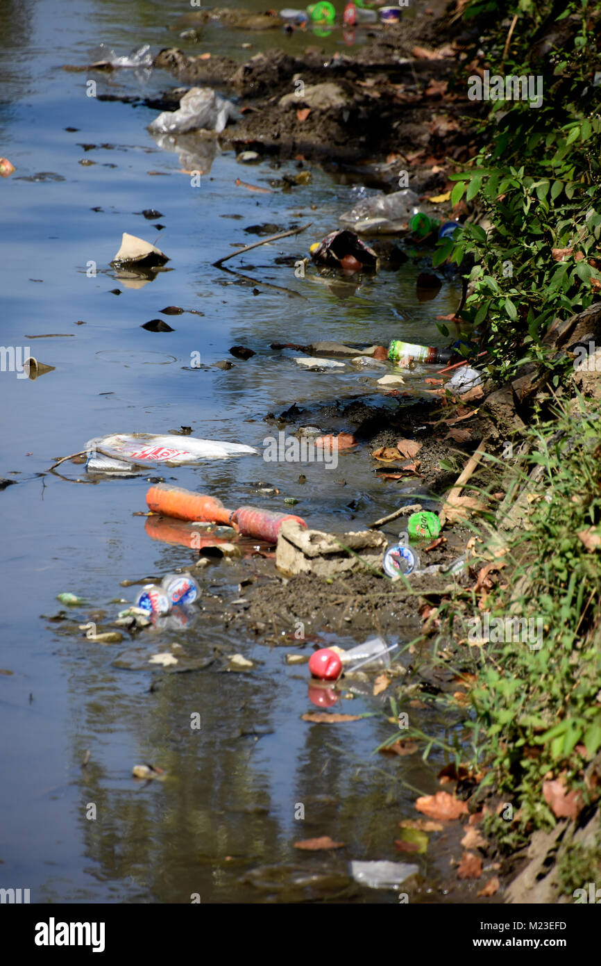 Rubbish flowing down a small river in Indonesia, next to a slum area called the painted village Stock Photo