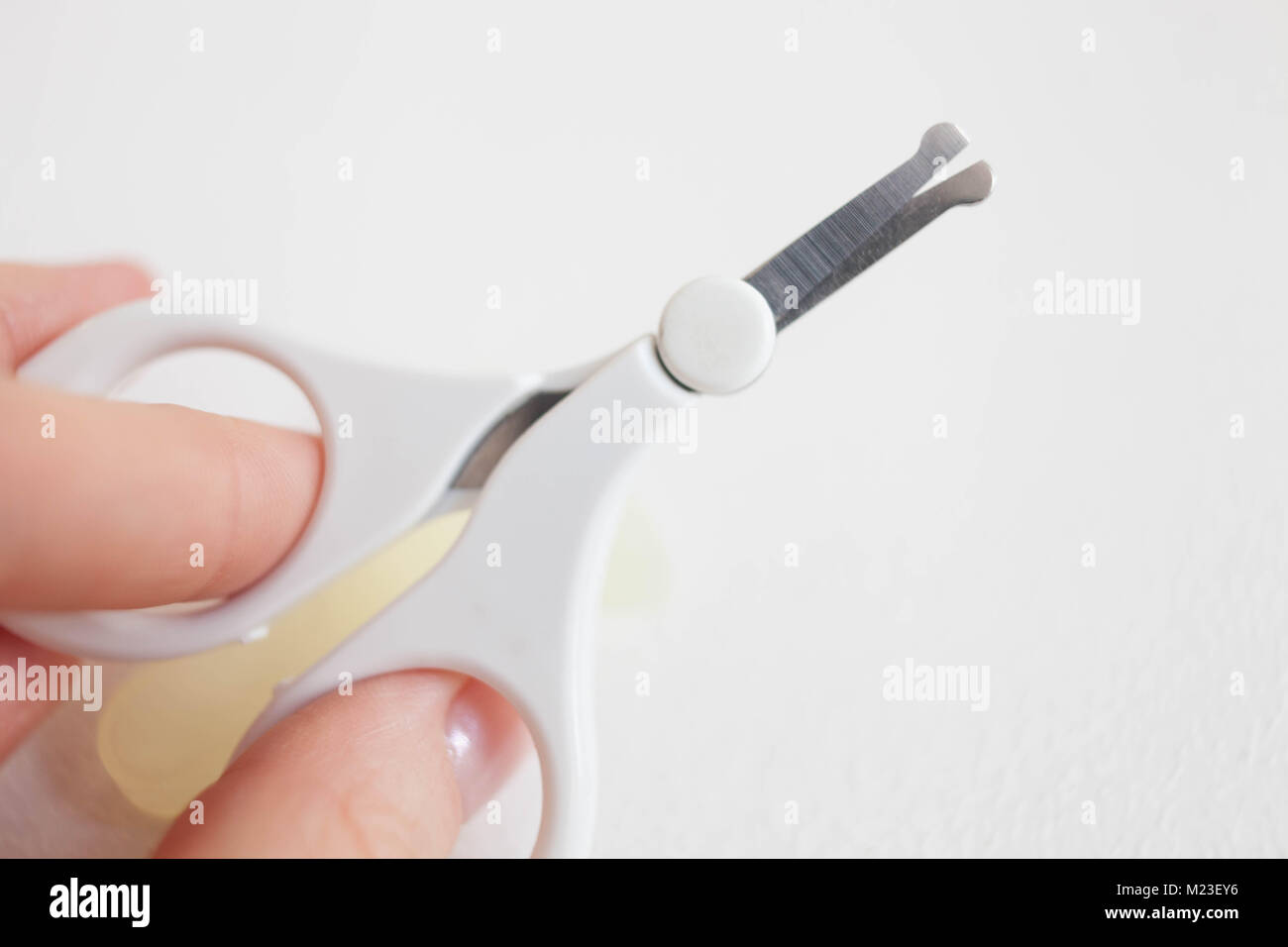 Baby scissors with rounded ends in the hands of his mother on a white background. Stock Photo