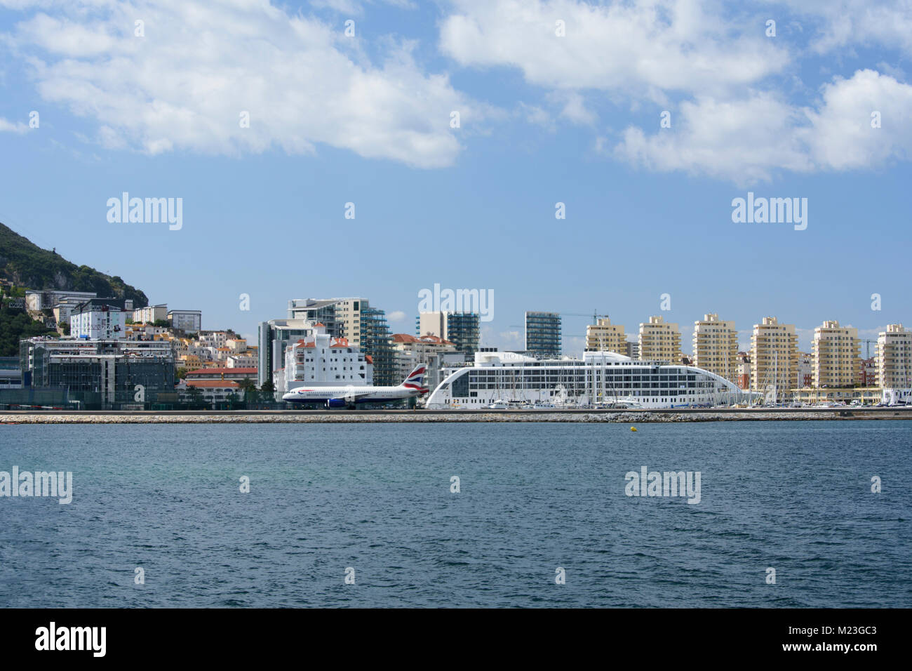 Gibraltar, A landing plane passes a large cruise ship. Stock Photo