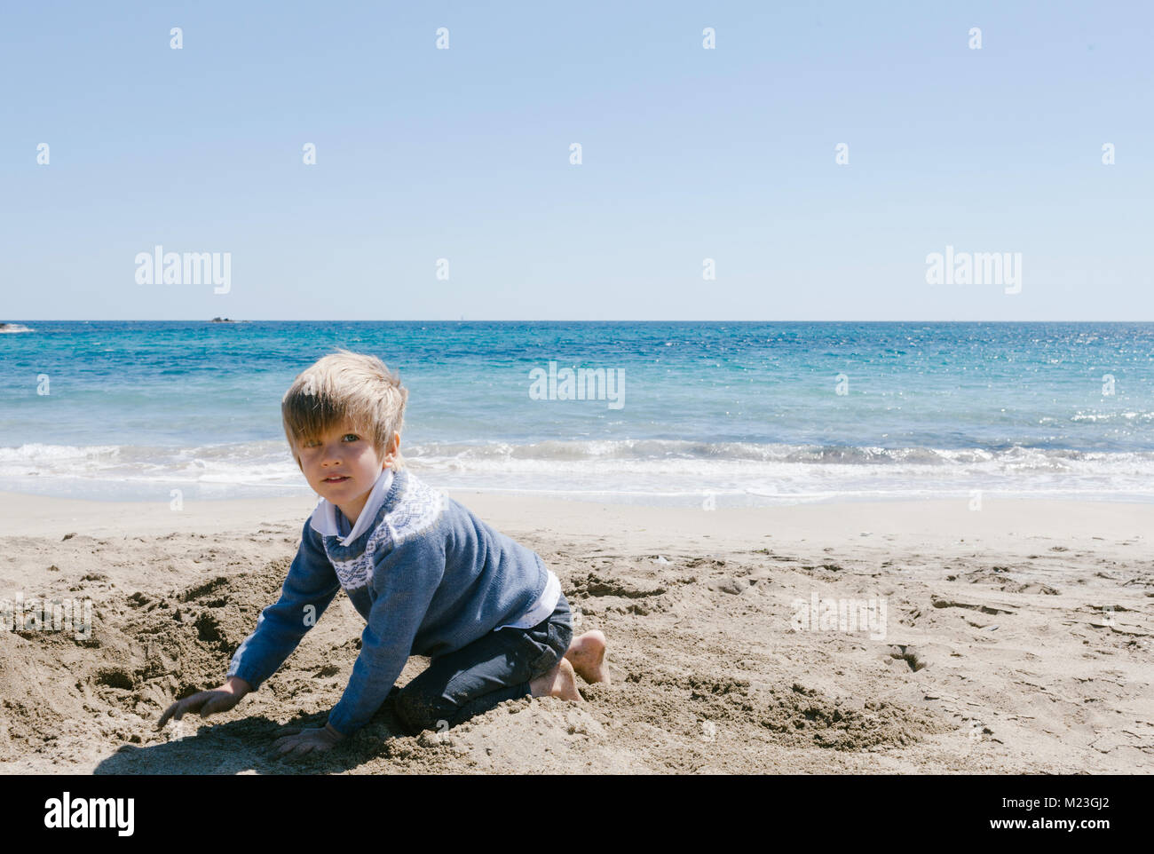 blond boy with blue eyes playing on the beach in winter Stock Photo