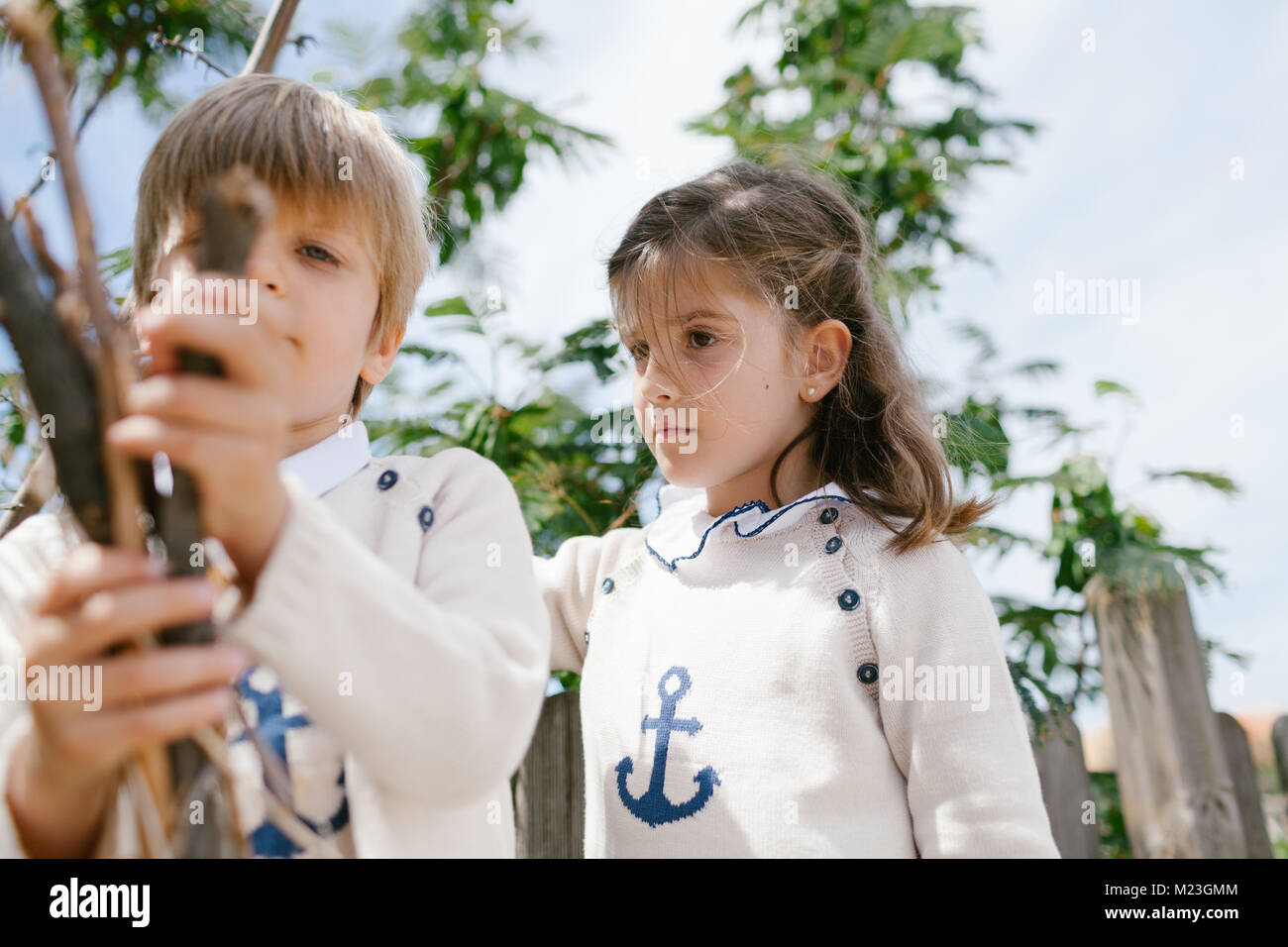 serious girl looks at the toys of her blond brother Stock Photo