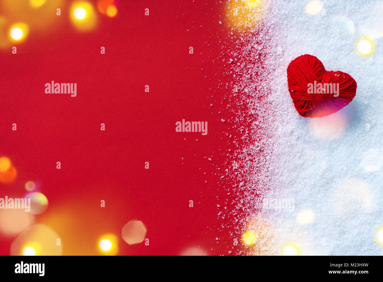 Red heart of wool yarn on snow and red background. Love and St. Valentines Day concept Stock Photo