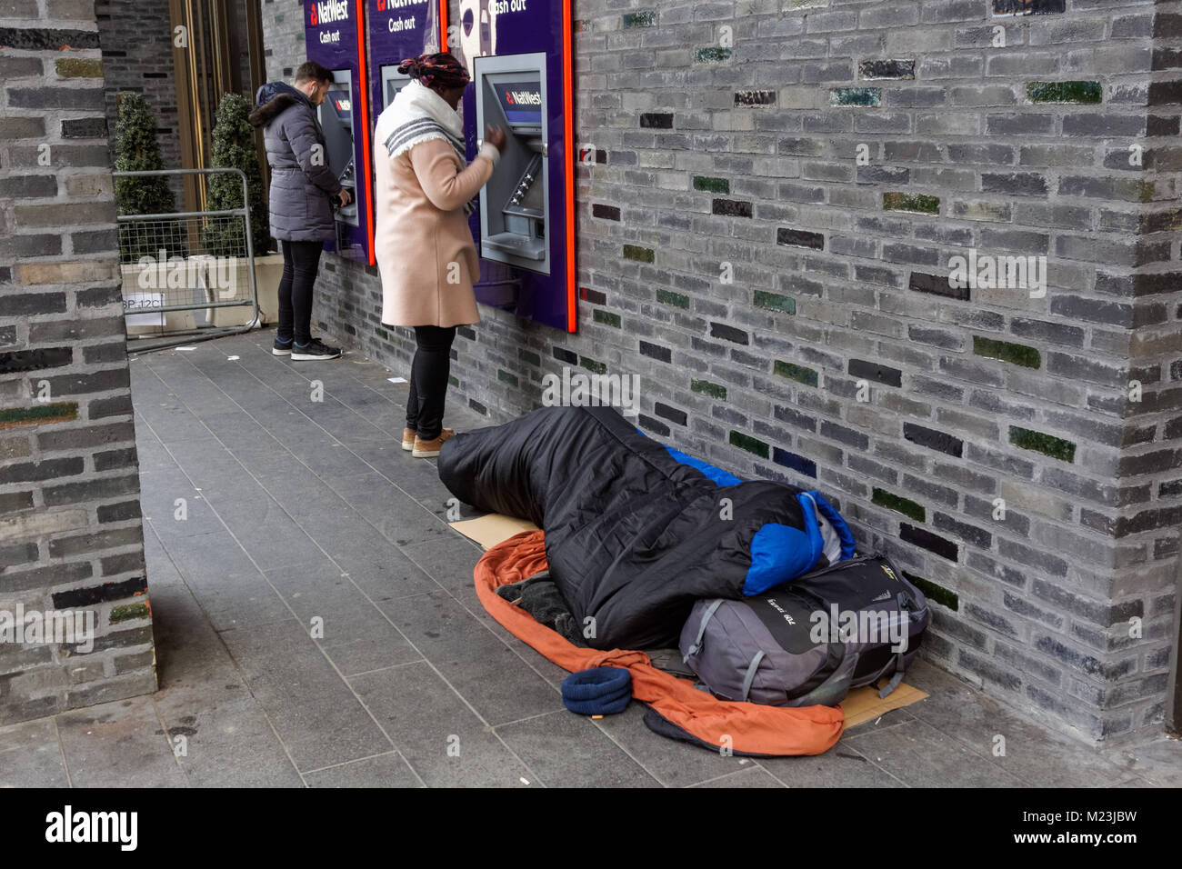 Person sleeping rough next to Natwest ATM cash machines in London, England, United Kingdom, UK Stock Photo
