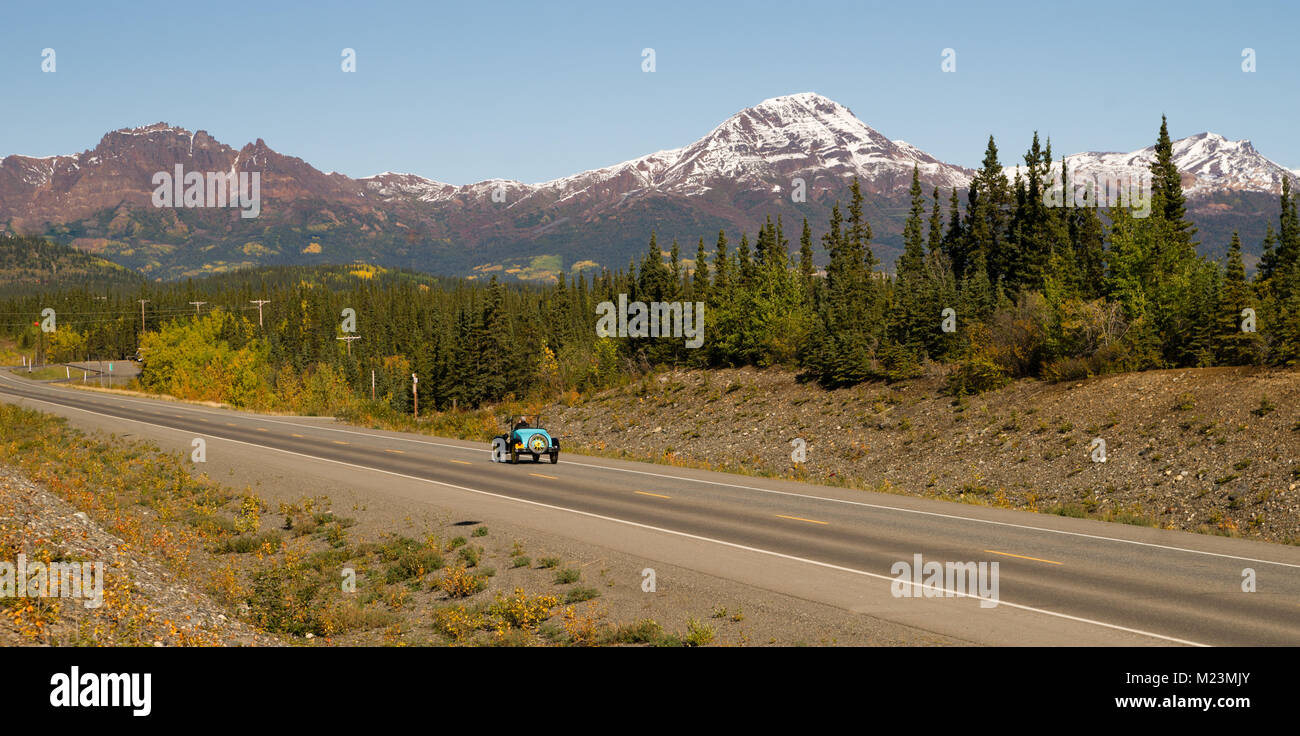 Long panoramic vintage car moves along north Alaska highway North America Stock Photo