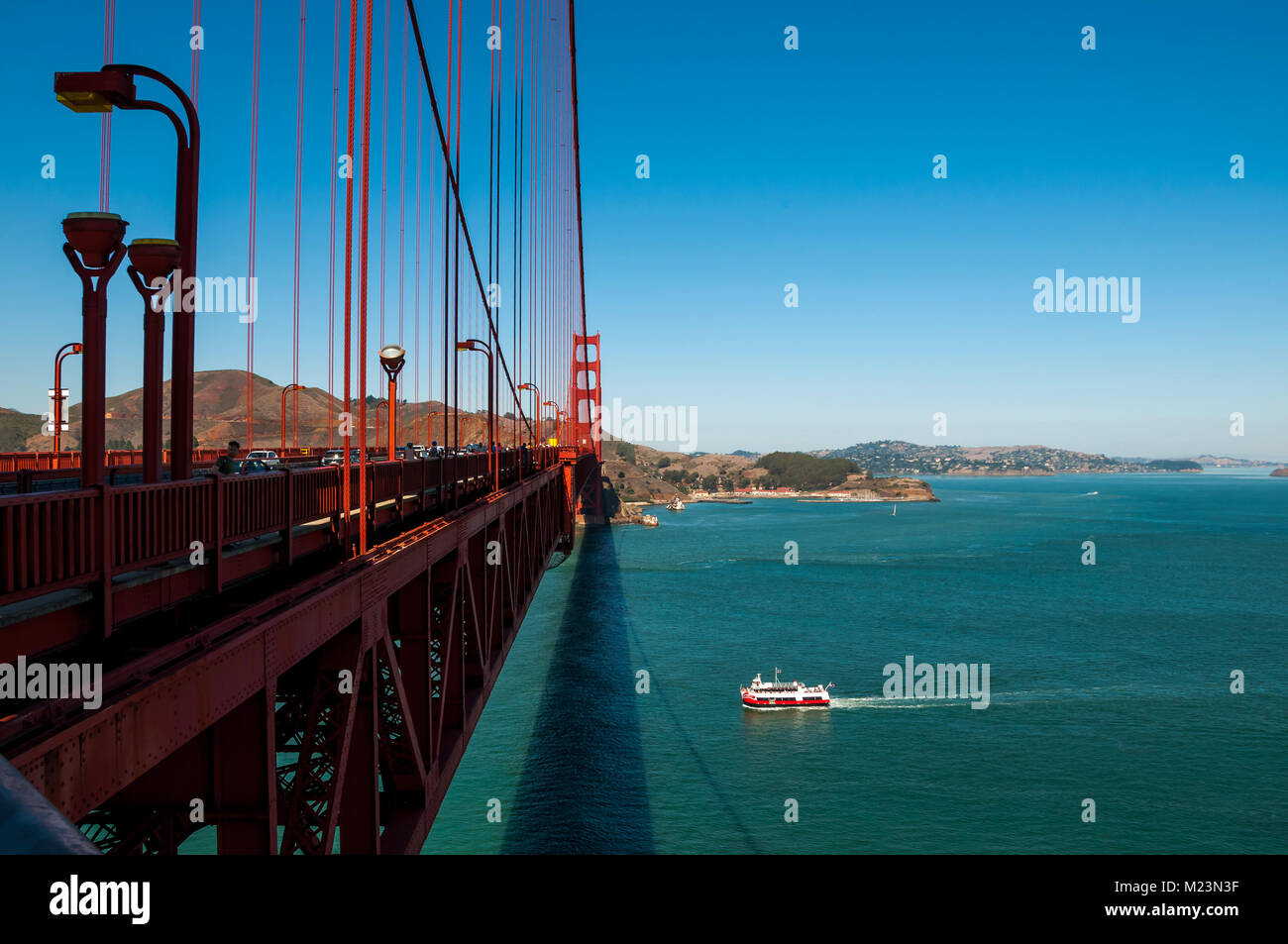 SAN FRANCISCO, CALIFORNIA - SEPTEMBER 8, 2015 - Golden Gate Bridge with pedestrians crossing and boat passing under Stock Photo