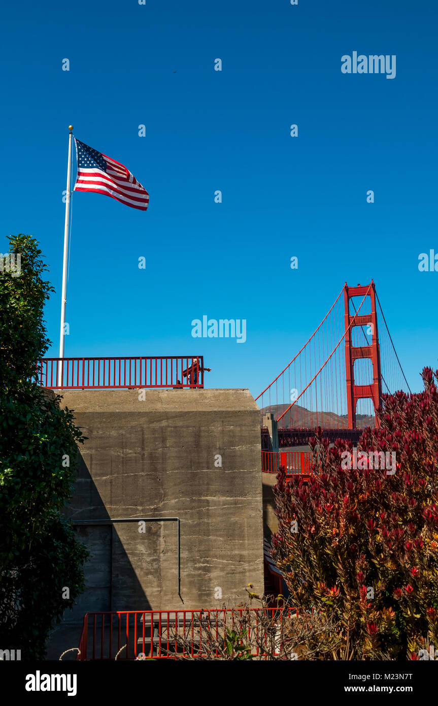 SAN FRANCISCO, CALIFORNIA - SEPTEMBER 8, 2015 - The American flag flying in the wind with Golden Gate Bridge and bright blue sky in the background Stock Photo