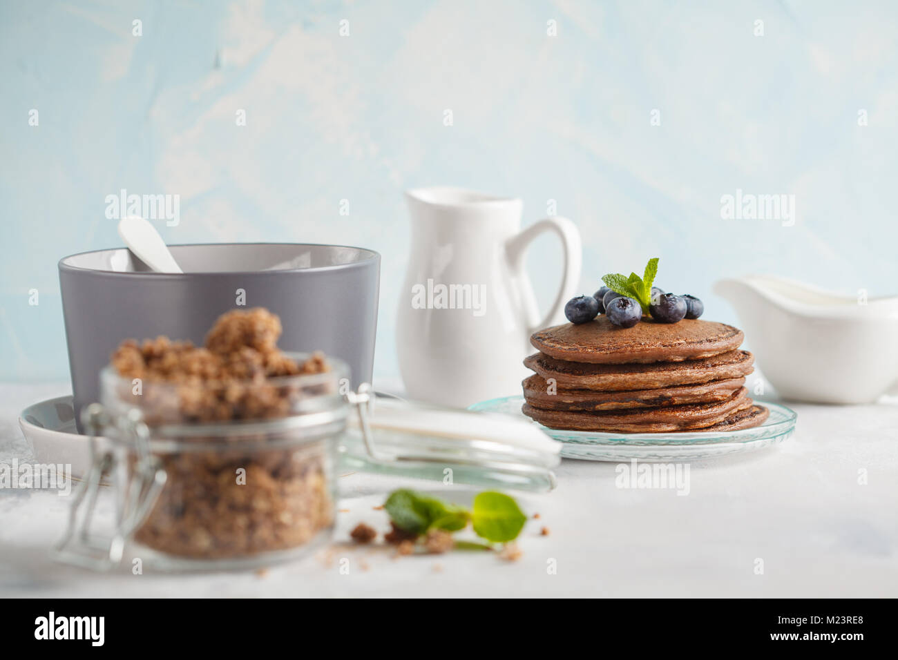Chocolate pancakes, chocolate baked granola in a jar and milk. Healthy