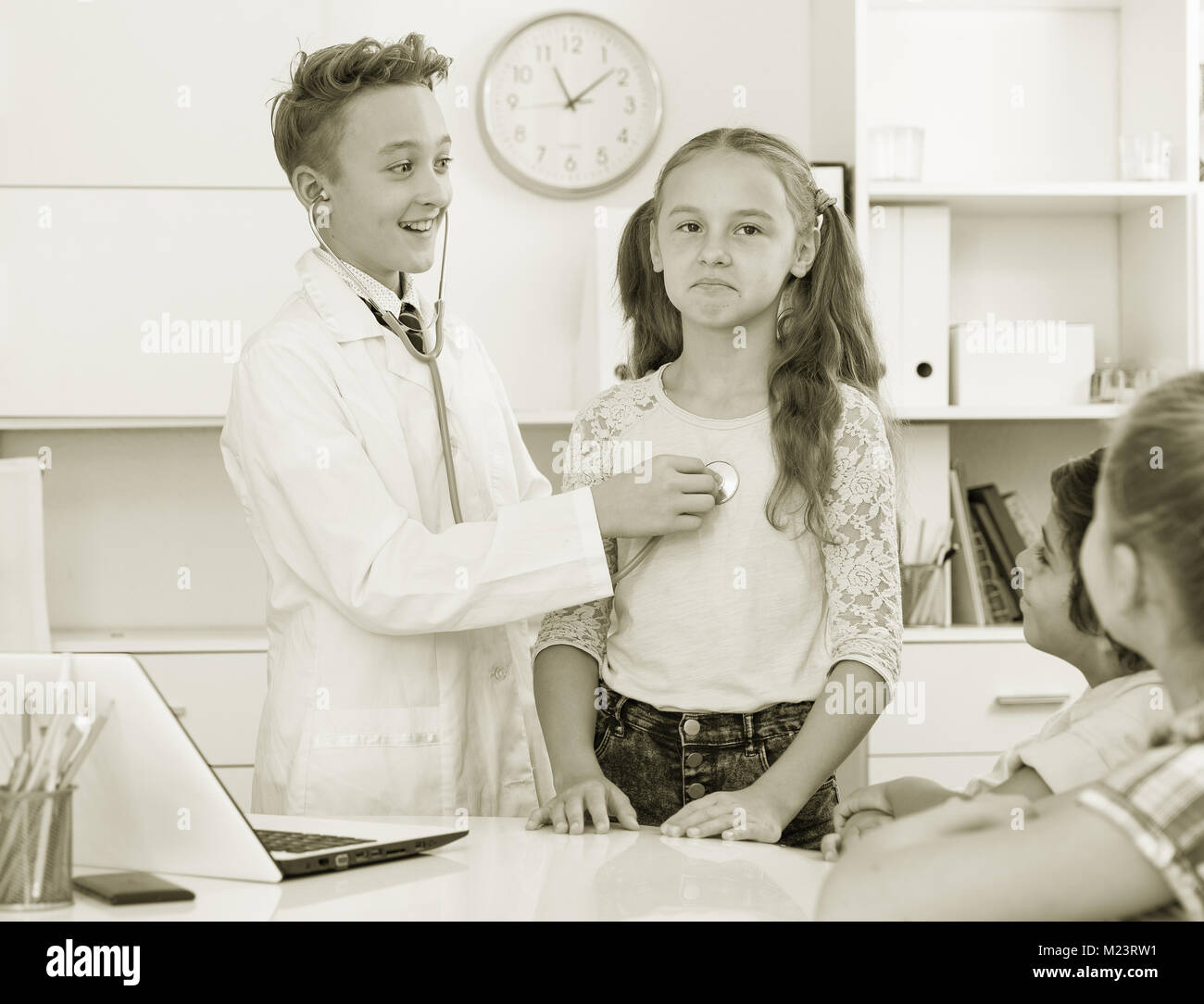 Young male doctor in uniform leading medical appointment with children Stock Photo