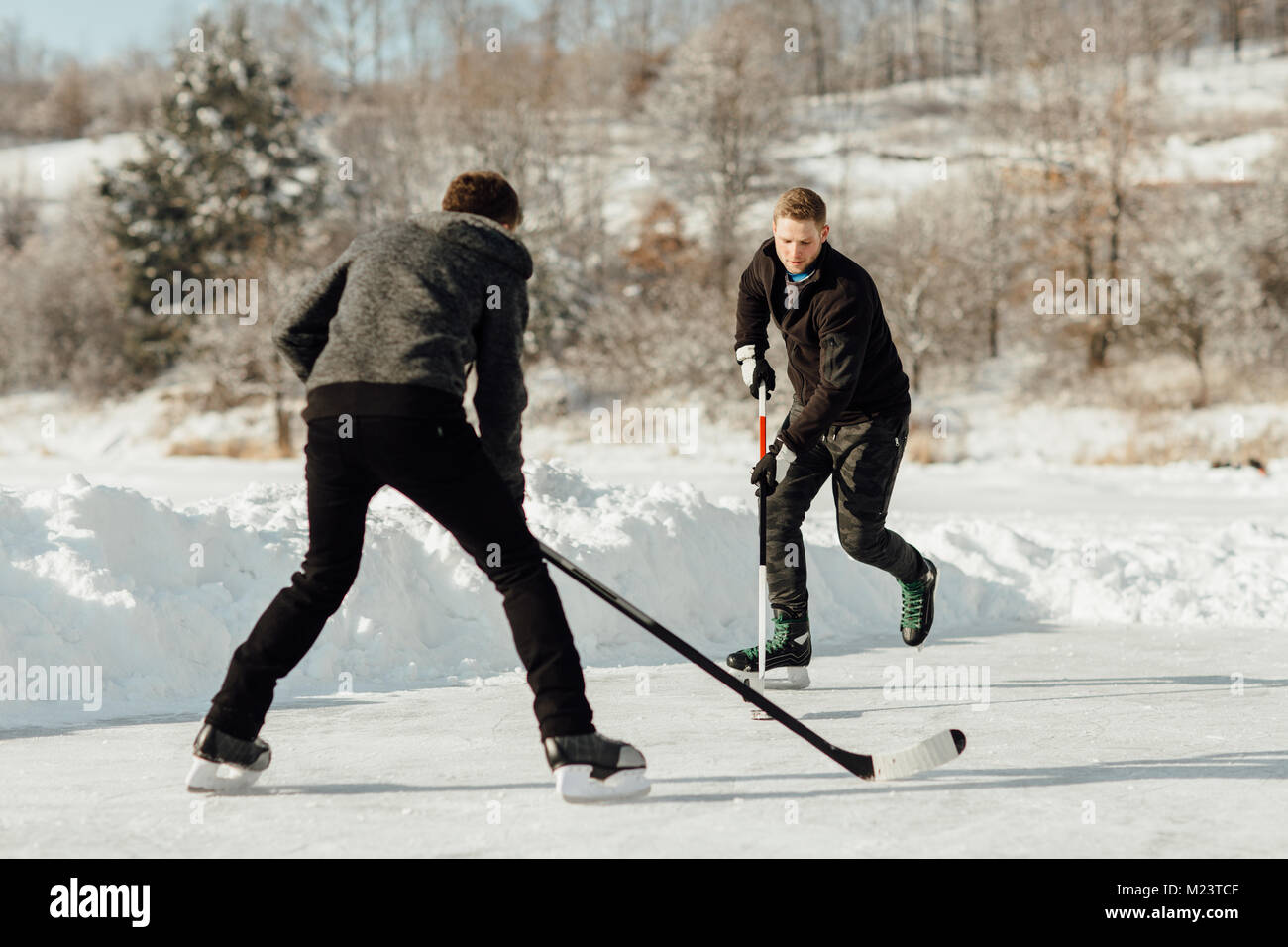 Two men playing ice hockey on a frozen lake Stock Photo