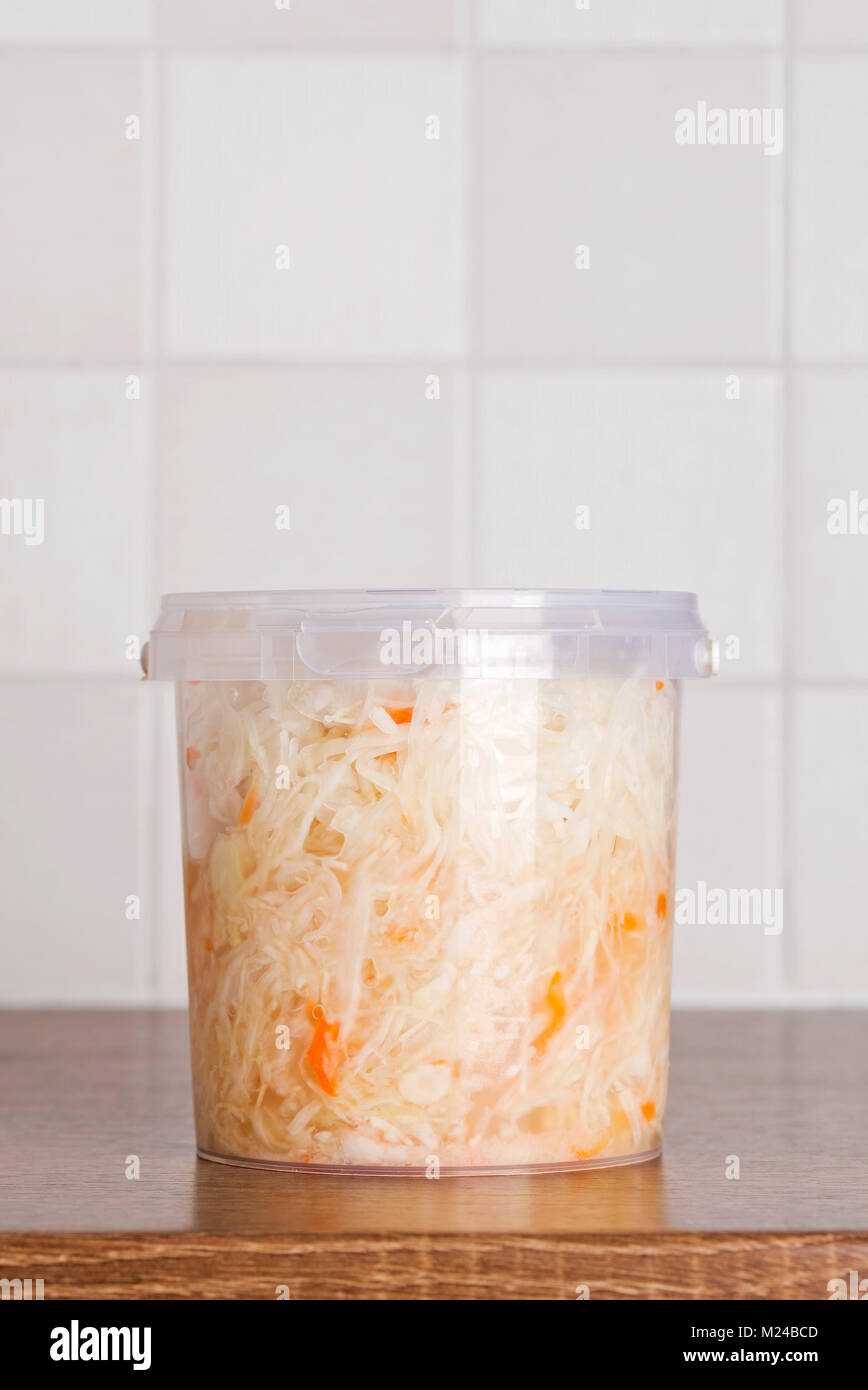 Marinated cabbage in plastic bucket standing on the kitchen table Stock Photo
