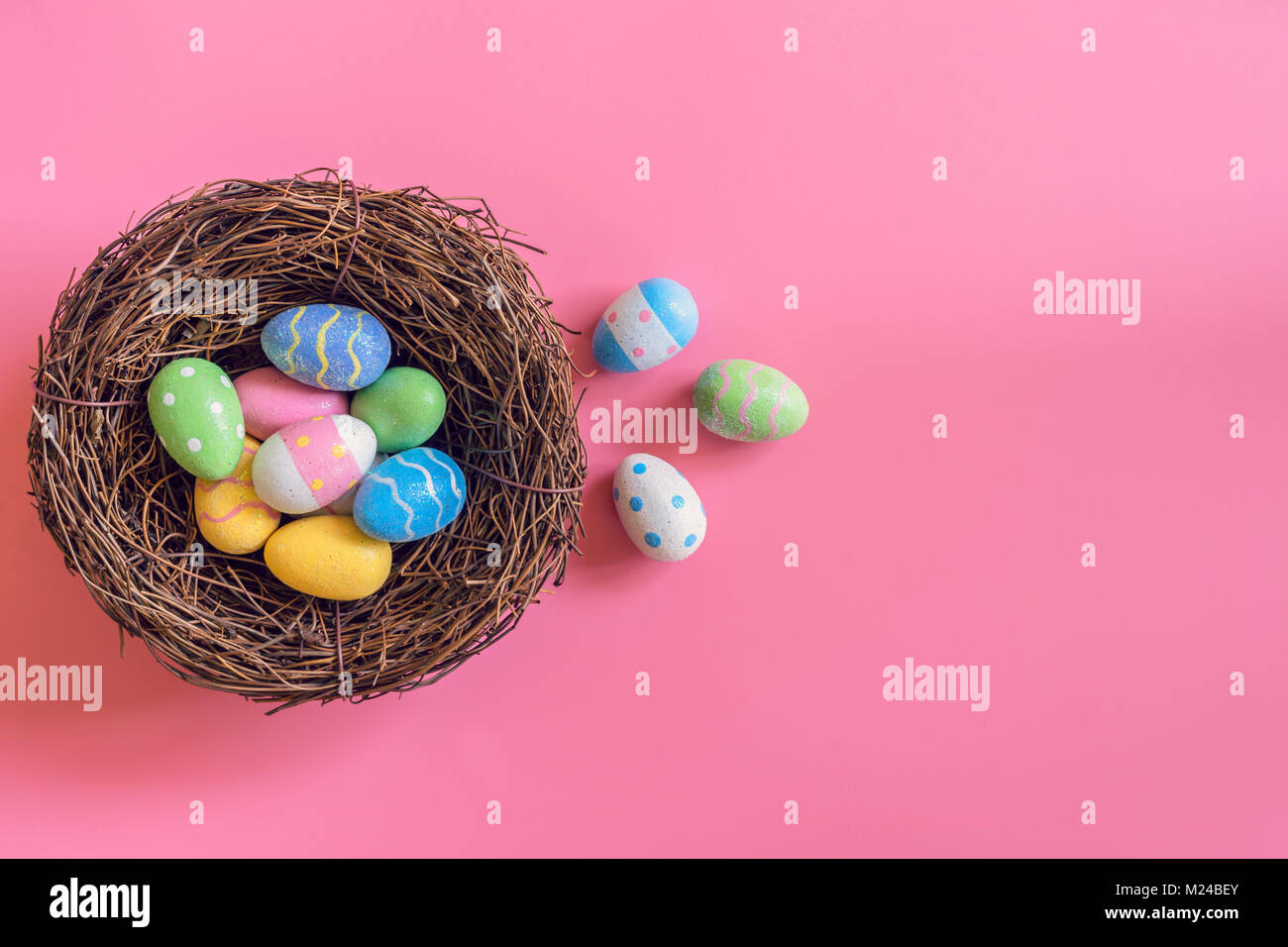 Colorful easter eggs in nest on pink pastel color background with space ...