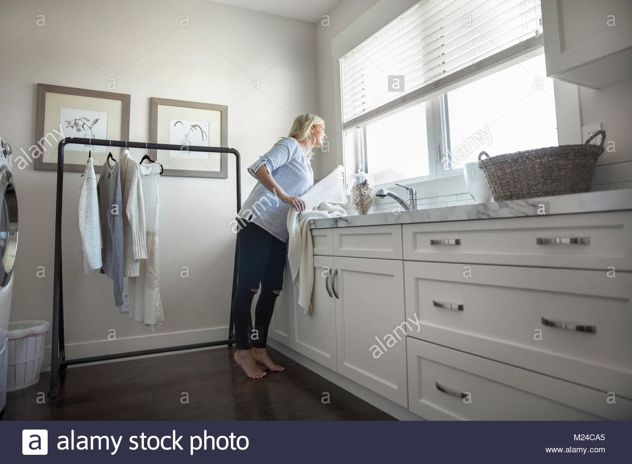 Woman Folding Laundry At Counter In Laundry Room Stock Photo