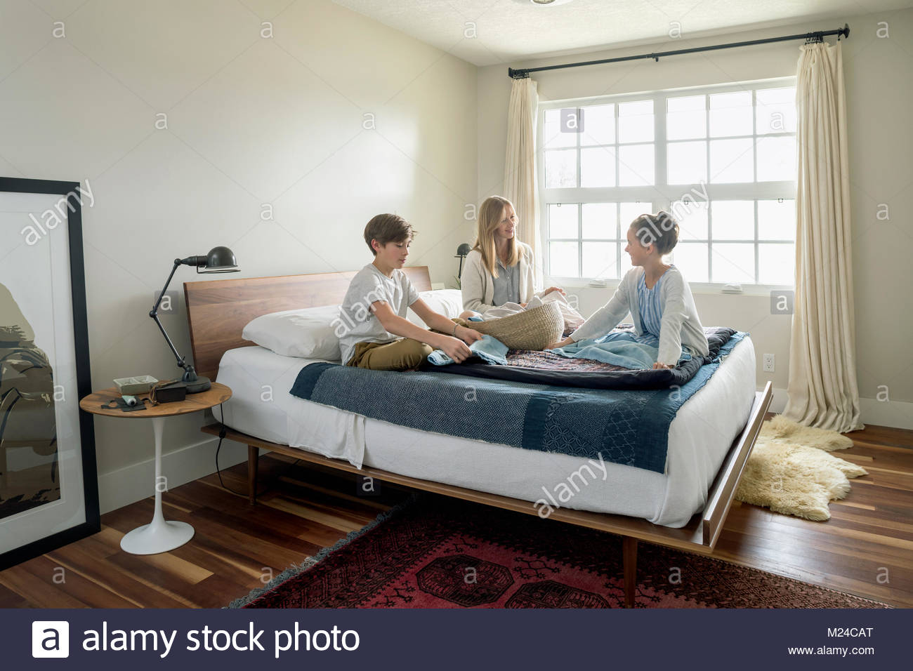Mother and children folding laundry on bed Stock Photo