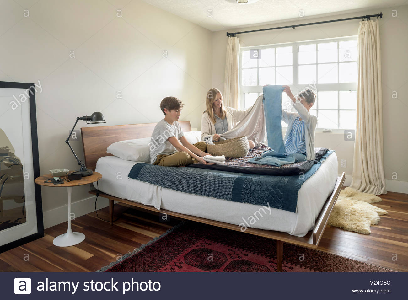 Mother and children folding laundry on bed Stock Photo