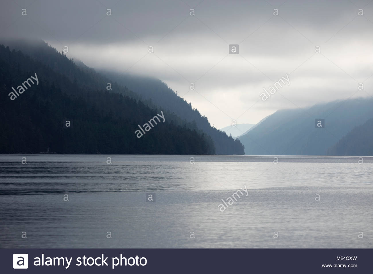 Tranquil silhouetted mountains and lake under cloudy sky Stock Photo