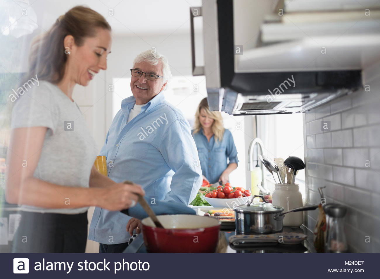 Smiling daughter and senior father cooking at stove in kitchen Stock Photo