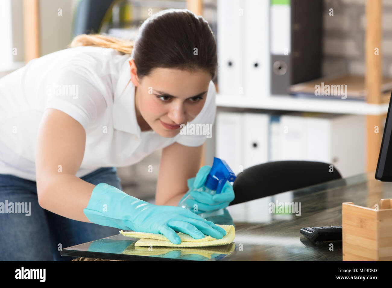 Happy Young Woman Cleaning The Glass Office Desk With Rag Stock Photo