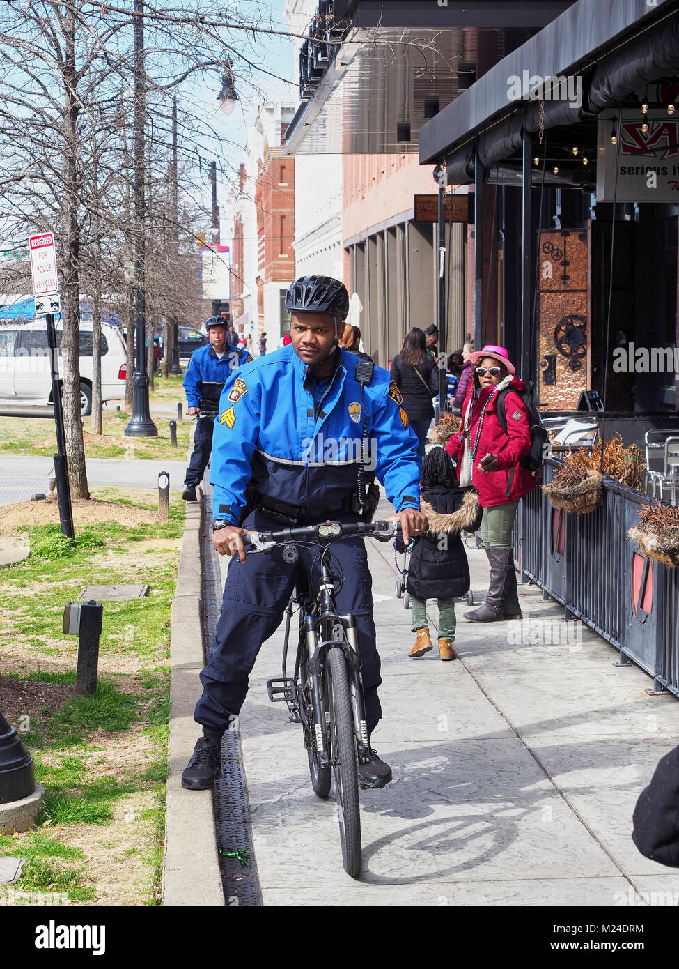 African American, or black, police officer on a bicycle conducts routine patrol on a city sidewalk in downtown Montgomery Alabama, United States. Stock Photo