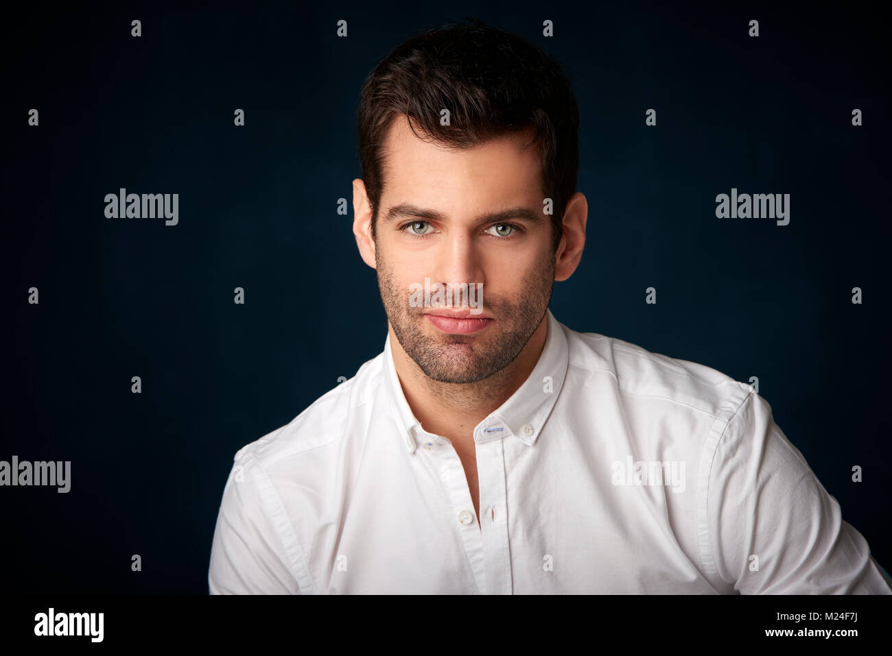 Studio portrait of confident young man wearing shirt and looking at ...