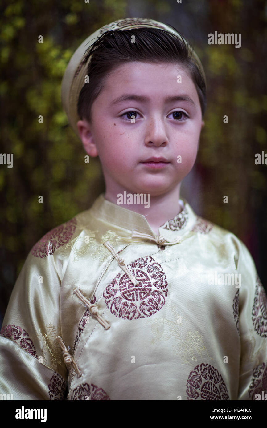 Mixed race Asian Caucasian little boy dressed in gold colored traditional Vietnamese costume Ao Dai celebrating Lunar New year harvest festival Tet Stock Photo