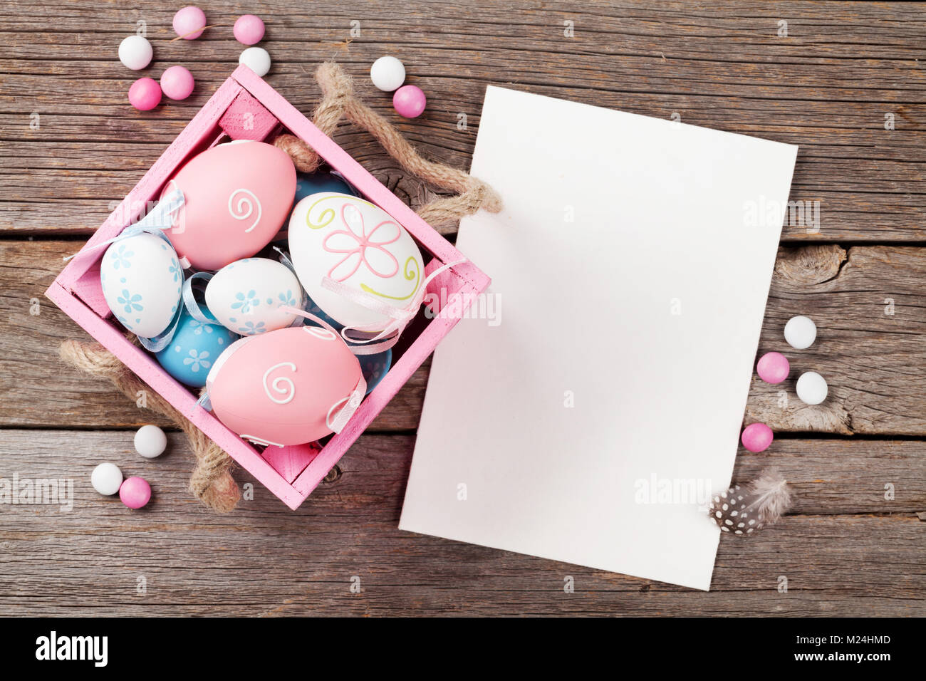 Easter eggs in box and greeting card on wooden table. Top view with ...