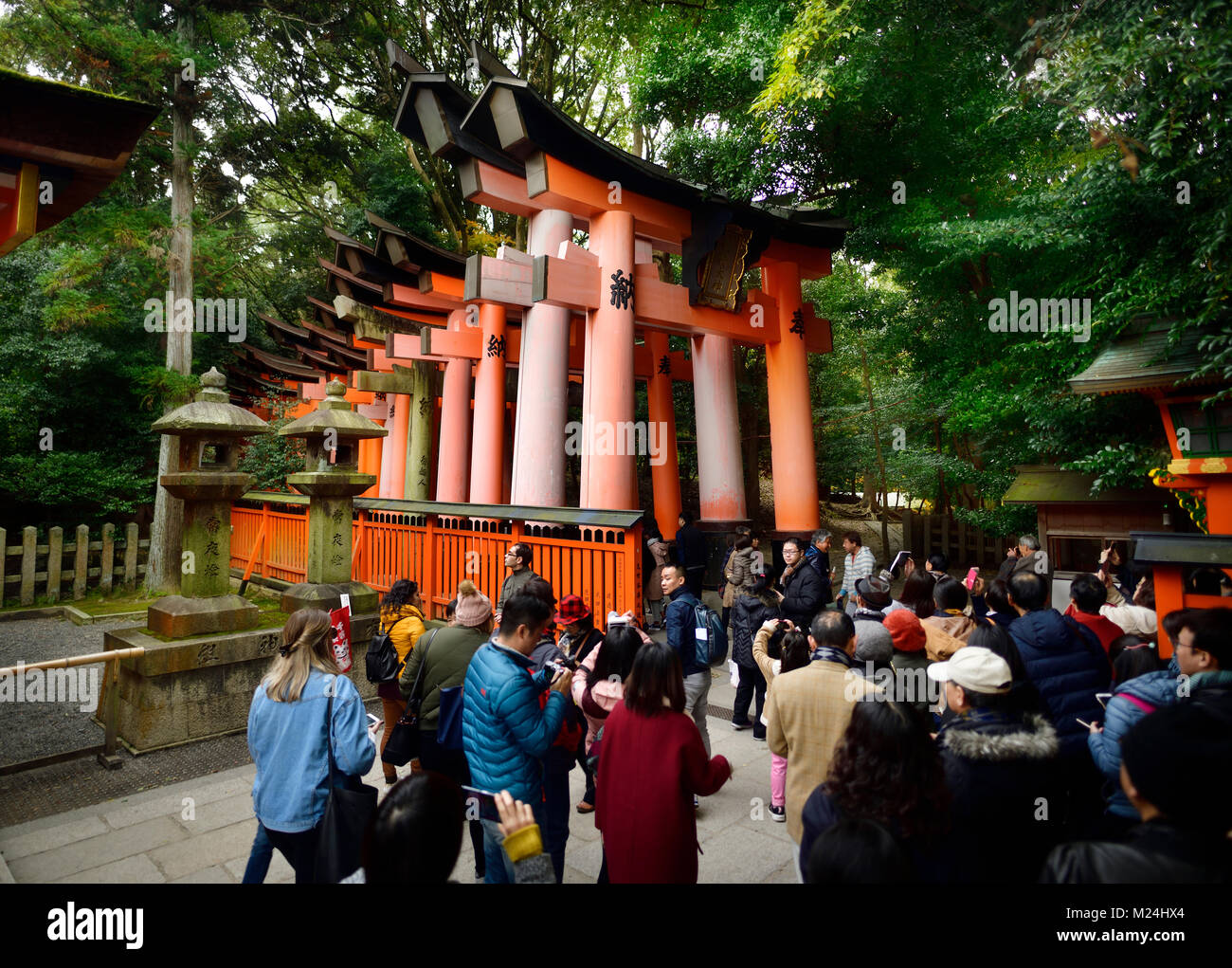 Tourists entering Senbon Torii path leading to inner shrines of Fushimi Inari Taisha head shrine in Fushimi Ward, Kyoto, Japan 2017 Stock Photo