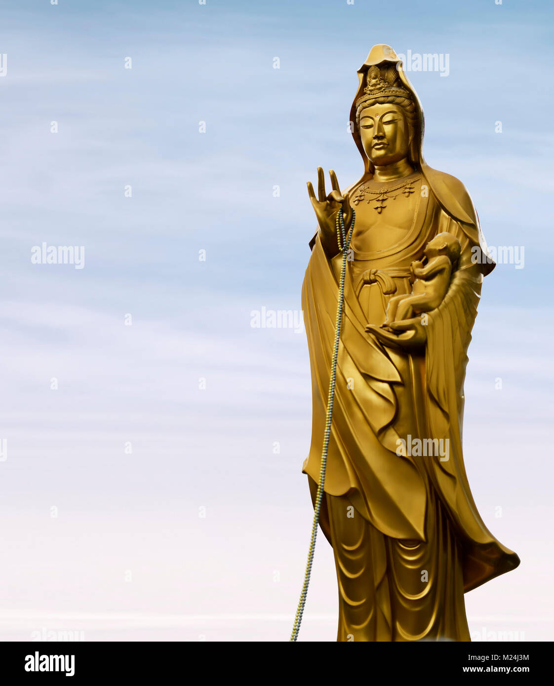 Bronze statue of Guanyin, female Buddha, the Goddess of Compassion, cradles a baby in her hand, Mother Goddess. Also know as Guan Yin, Kuan Yin, Kanno Stock Photo