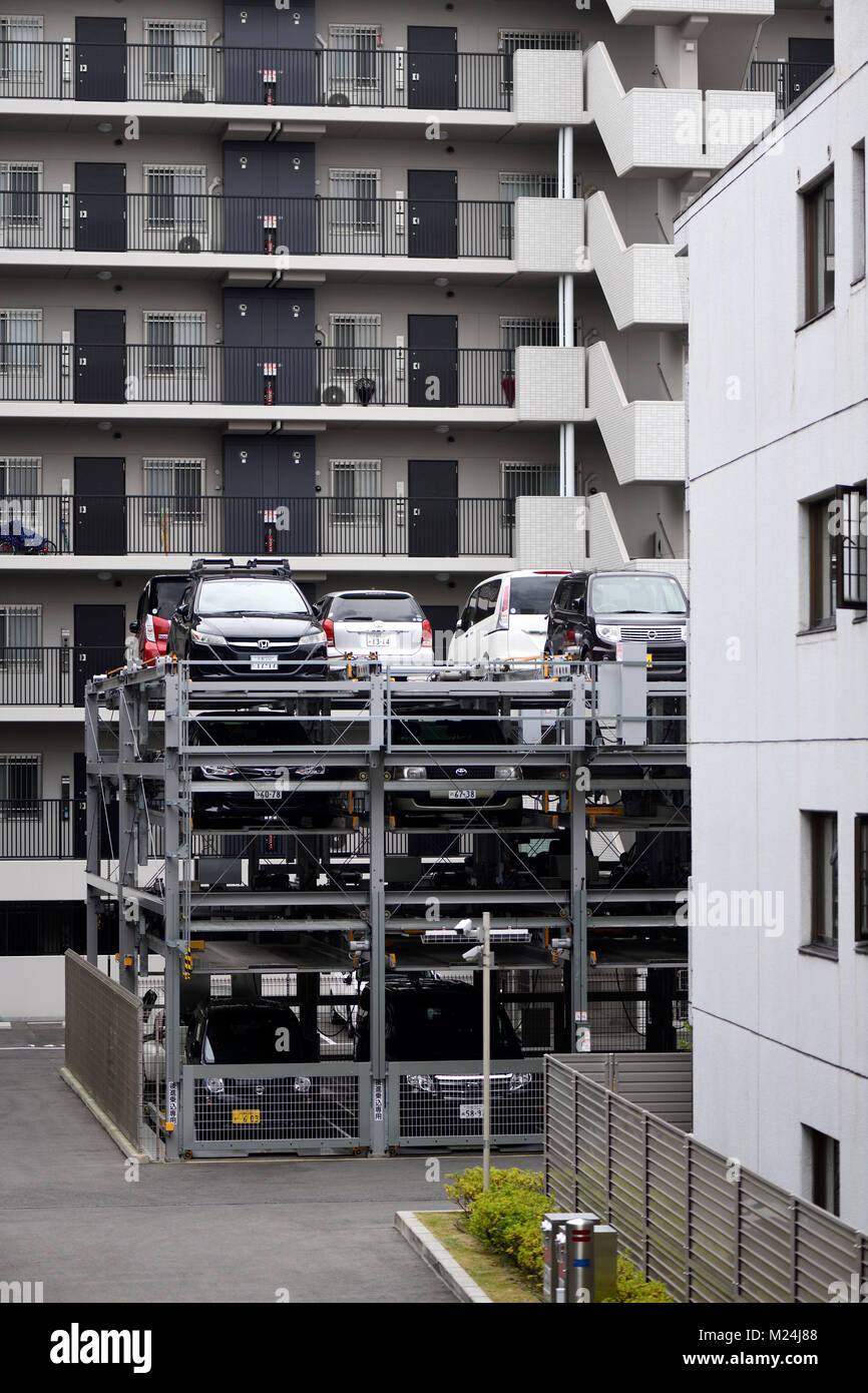 Cars parked in a multi-level vertical three-storey automated parking lot with a lift by an apartment building in Kyoto, Japan 2017 Stock Photo