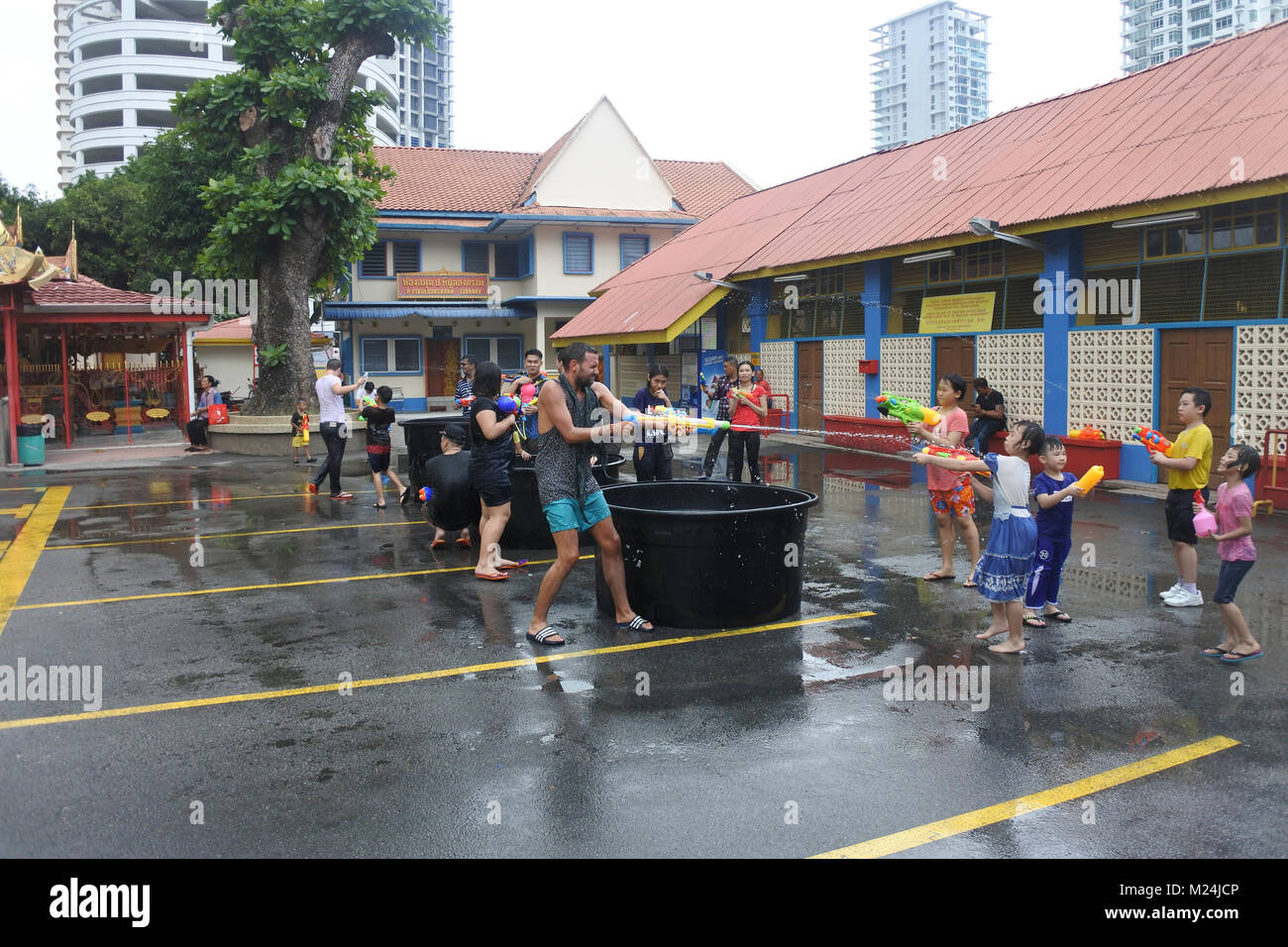 People at the Songkran festival throwing water in buckets at each other from a alrge tank of water, water is frozen in motion Stock Photo