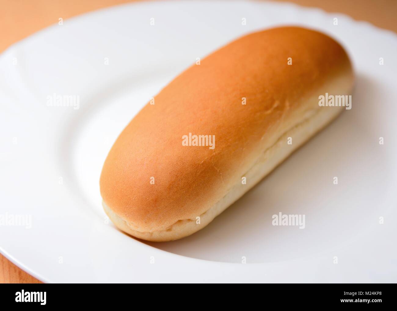 Closeup of a soft plain hot dog bun on a white plate. Stock Photo