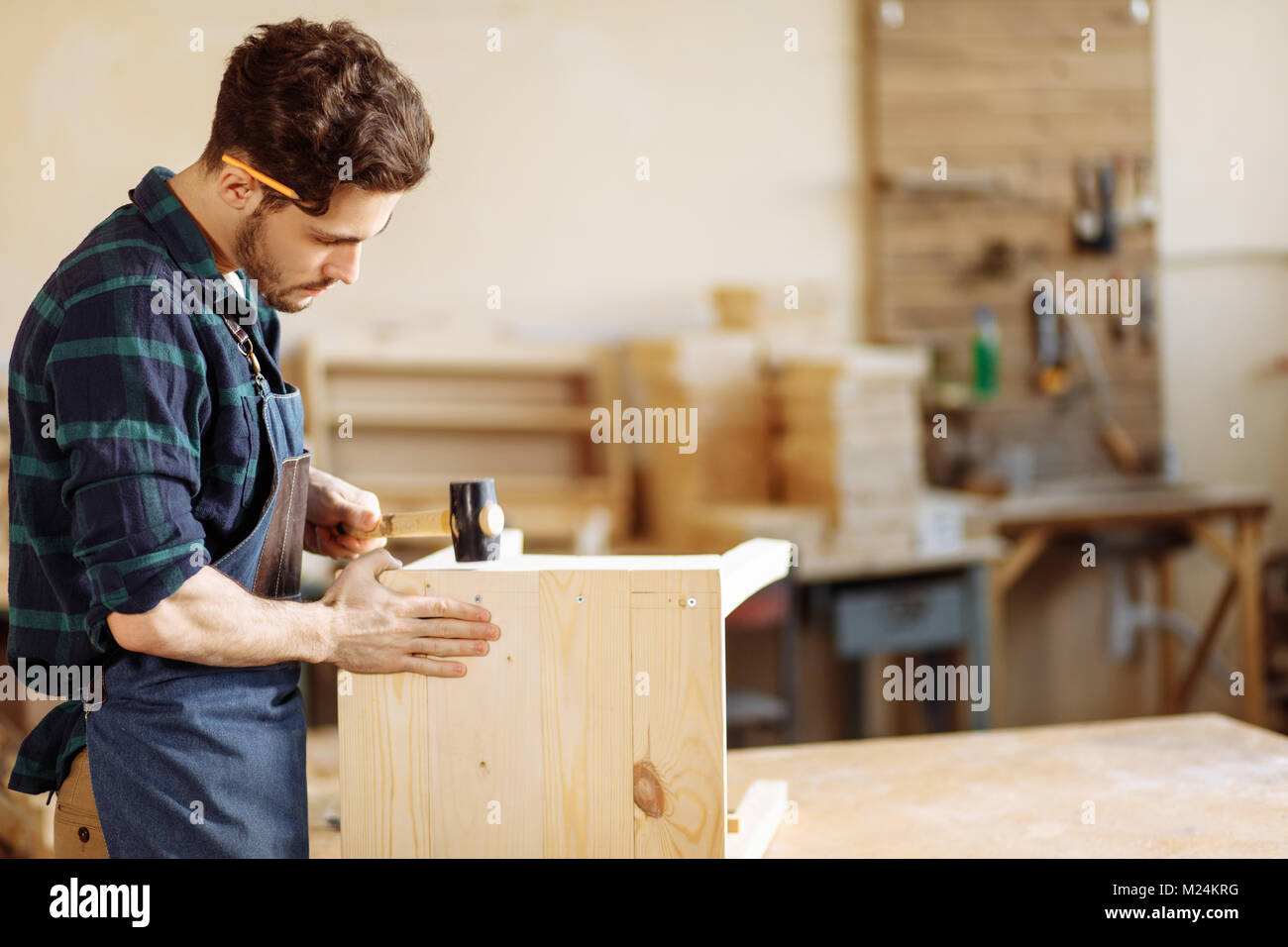 carpenter hammering a nail into wooden board Stock Photo - Alamy