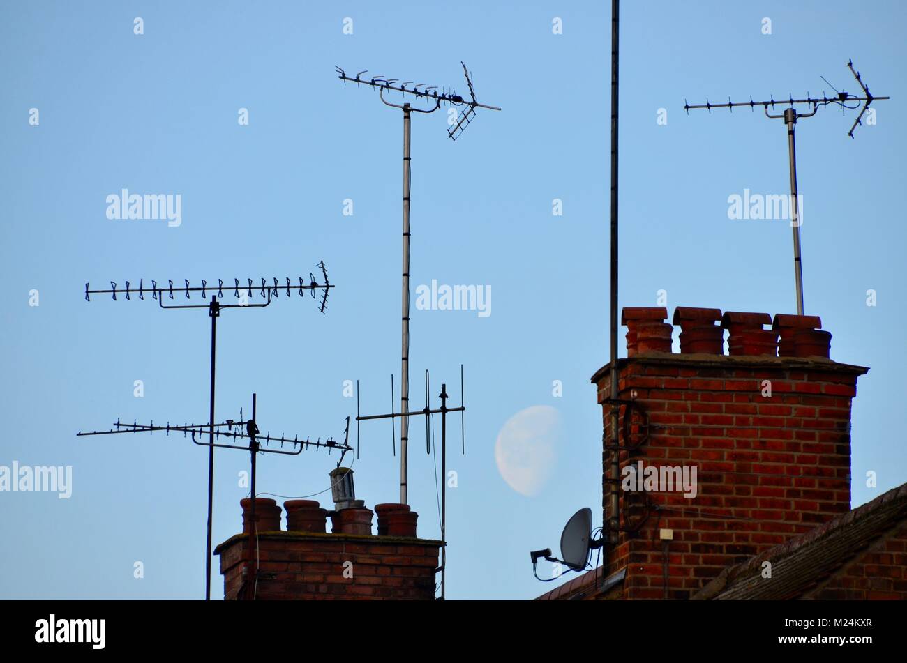 aerials and chimneys on london houses with a large moon behind Stock Photo
